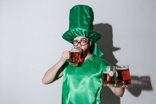 Hombre en traje de patriotas bebiendo cerveza y sosteniendo copas