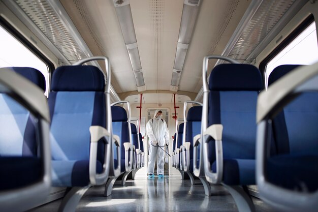 Hombre con traje de protección blanco desinfectando y desinfectando el interior del tren subterráneo para detener la propagación del virus corona altamente contagioso