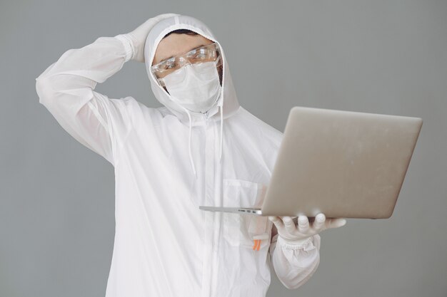 Hombre con traje protector y gafas en pared gris