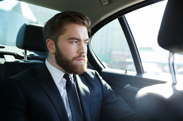 Hombre en traje sentado en el asiento trasero del automóvil