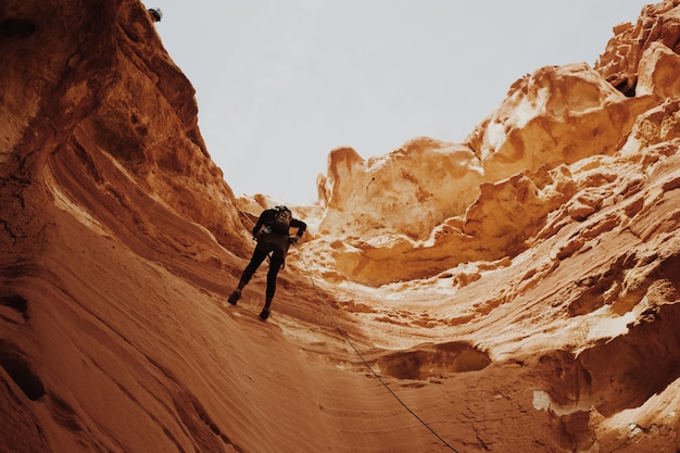 Foto gratuita hombre tratando de escalar los acantilados del cañón