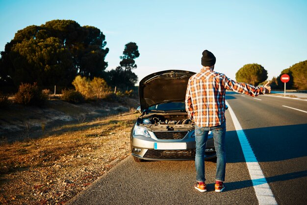 Hombre tratando de obtener ayuda con su coche roto