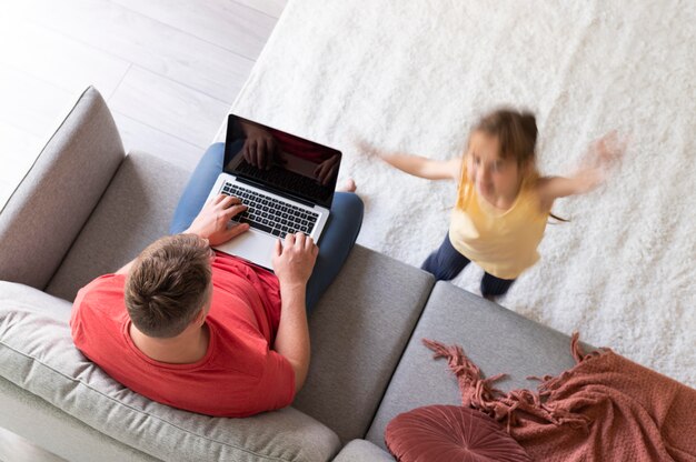 Hombre tratando de trabajar en la computadora portátil desde casa mientras sus hijos corren