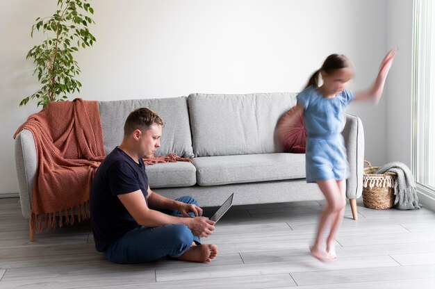 Hombre tratando de trabajar en la computadora portátil desde casa mientras sus hijos corren