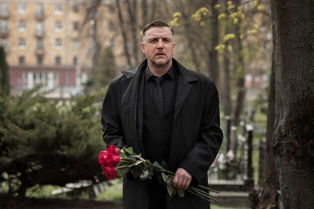 Hombre trayendo rosas a una lápida en el cementerio
