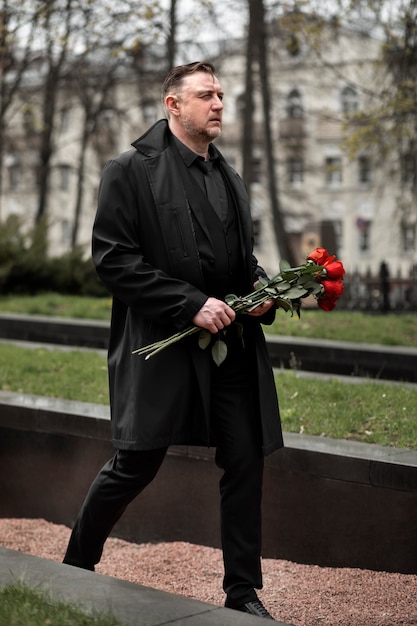 Hombre trayendo rosas a una lápida en el cementerio