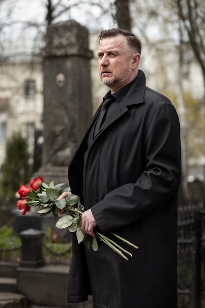 Foto gratuita hombre trayendo rosas a una lápida en el cementerio