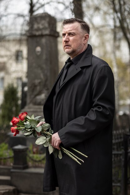 Hombre trayendo rosas a una lápida en el cementerio