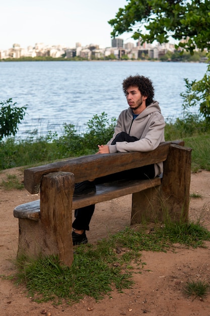 Hombre triste y contemplativo sentado junto al lago