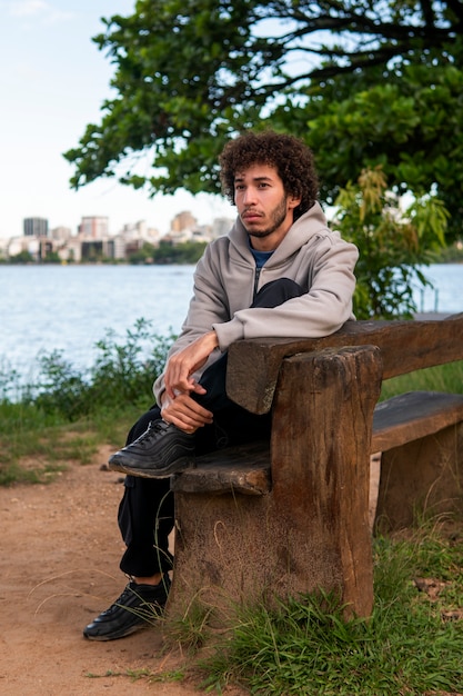 Foto gratuita hombre triste y contemplativo sentado junto al lago