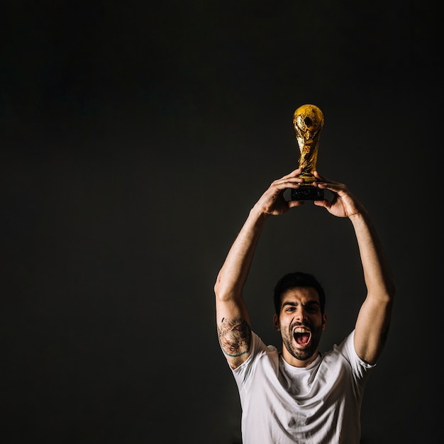 Foto gratuita hombre con el trofeo de la fifa celebrando la victoria