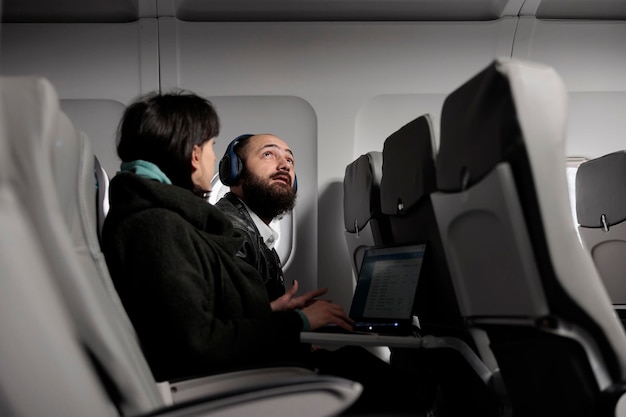 Foto gratuita hombre turista preparándose para despegar en avión, preparándose para volar con una aerolínea internacional. viajar en clase económica con una mujer para llegar al destino de vacaciones, transporte aéreo.