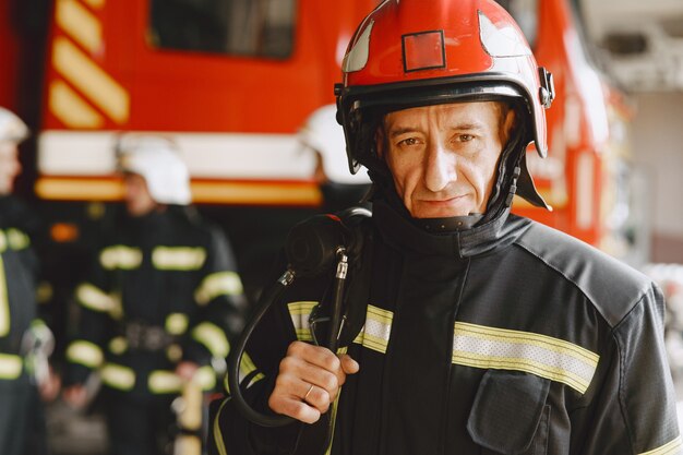 Hombre con uniforme de fuego. Bombero cerca del coche. Hombre, en, garaje