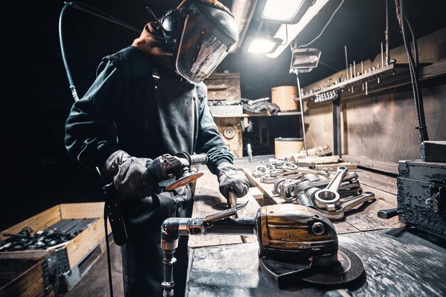 El hombre con uniforme y máscara protectora está trabajando en una fábrica de metal.