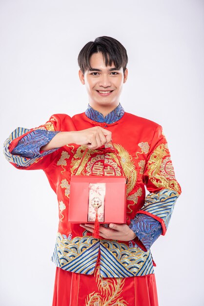 El hombre usa Cheongsam listo para darle una bolsa roja a su hermana para sorprender en el día tradicional