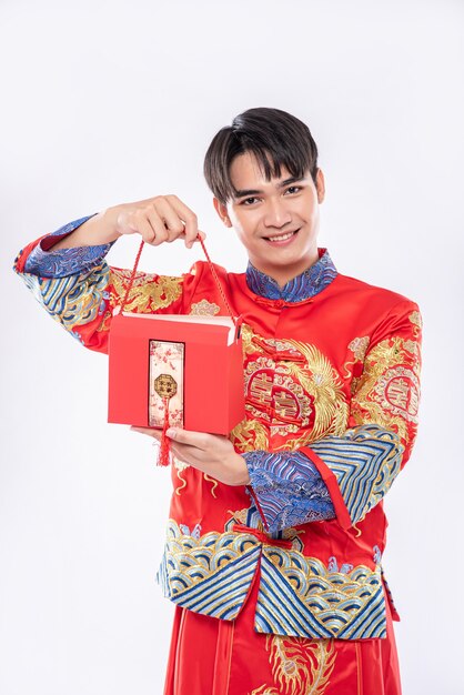 El hombre usa Cheongsam listo para darle una bolsa roja a su hermana para sorprender en el día tradicional