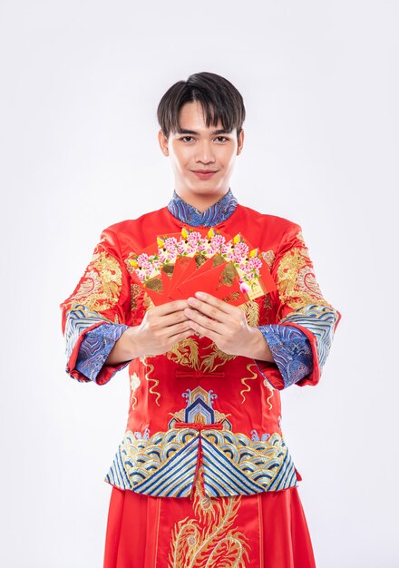 El hombre usa Cheongsam tiene mucha suerte de recibir dinero de regalo de los padres en un día tradicional