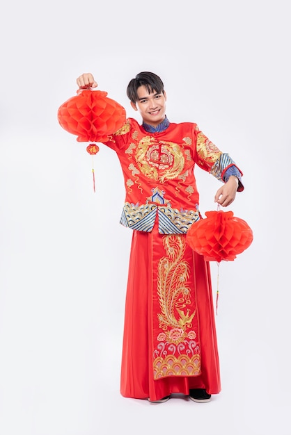 Hombre usa traje Cheongsam para decorar la lámpara roja de su tienda en el año nuevo chino