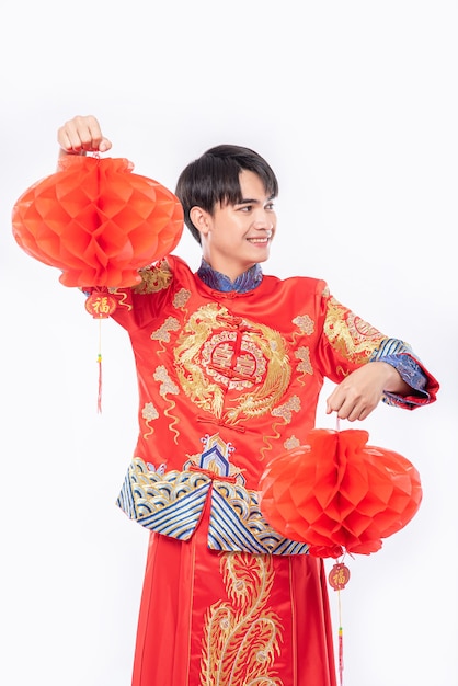 Hombre usa traje Cheongsam para decorar la lámpara roja de su tienda en el año nuevo chino