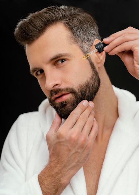 Foto gratuita hombre usando aceites naturales para su rostro