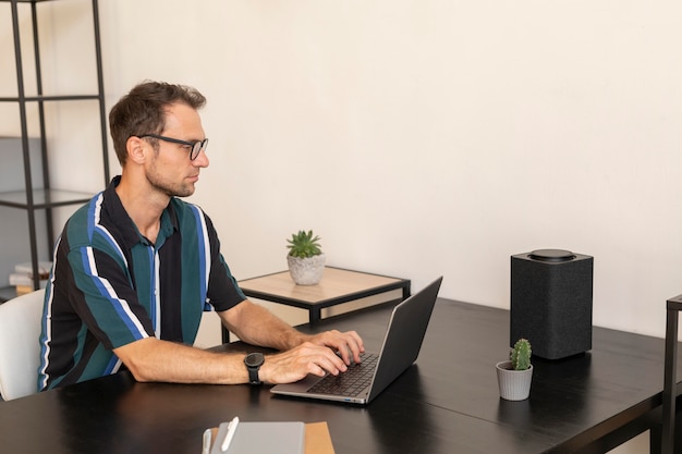 Hombre usando un altavoz inteligente mientras trabaja