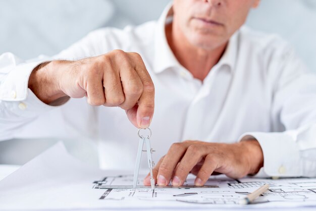 Hombre usando una brújula para plan arquitectónico