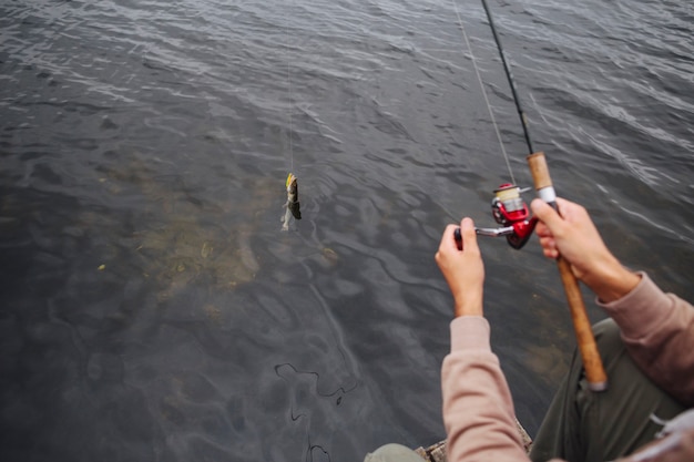 Hombre usando carrete de pesca para atrapar peces del lago