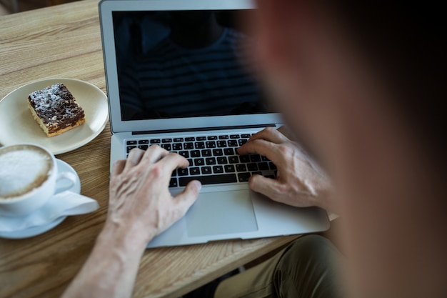 El hombre usando la computadora portátil en cafetería