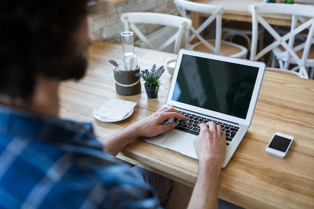 El hombre usando la computadora portátil en cafetería