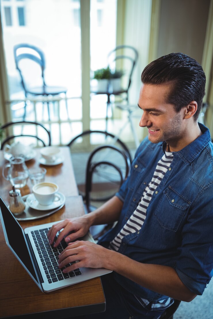 Foto gratuito el hombre usando la computadora portátil en la cafetería ©