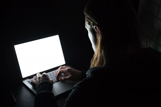 Hombre usando la computadora portátil en casa en el interior por la noche.