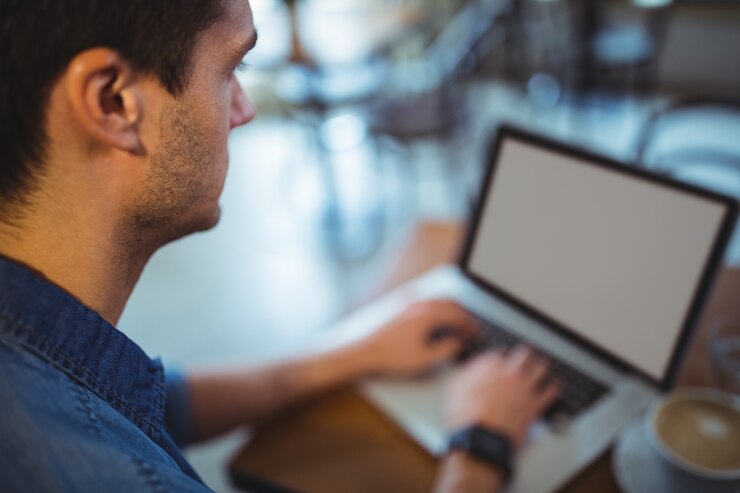 Foto gratuito el hombre usando la computadora portátil mientras que el café