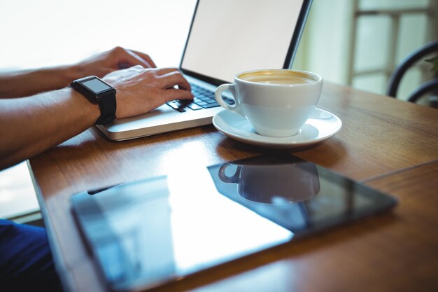 El hombre usando la computadora portátil mientras que el café