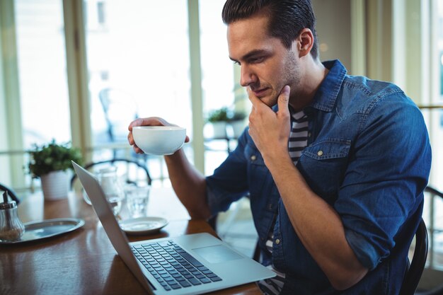 El hombre usando la computadora portátil mientras que el café