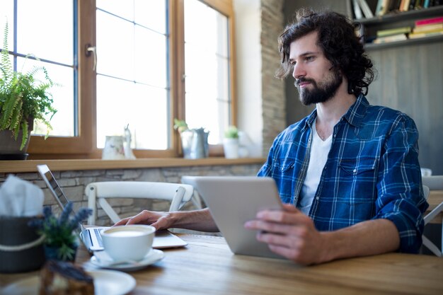 El hombre usando la computadora portátil y la tableta digital