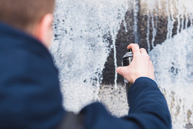 Hombre usando spray para dibujar graffiti en la pared