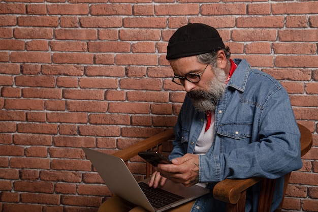 Hombre usando su computadora portátil por una pared de ladrillos