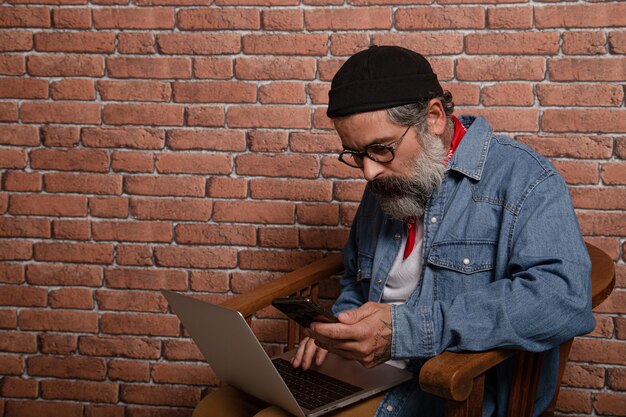 Hombre usando su computadora portátil por una pared de ladrillos