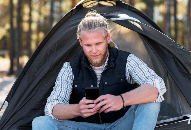 Foto gratuita hombre usando su teléfono móvil delante de la tienda