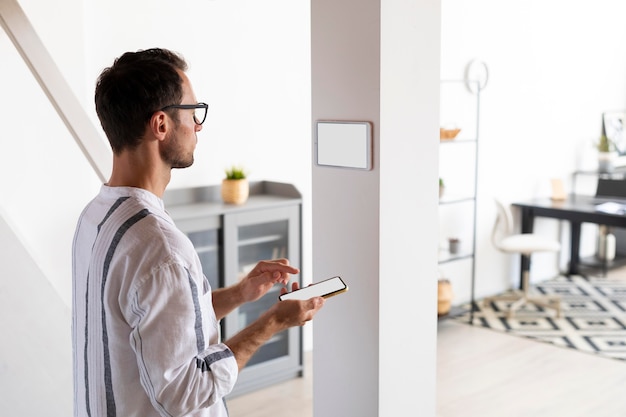 Hombre usando un teléfono inteligente en su hogar automatizado