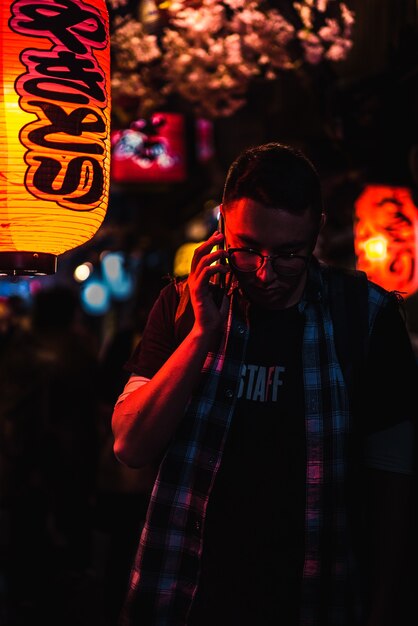 Hombre usando el teléfono mientras está de pie durante la noche