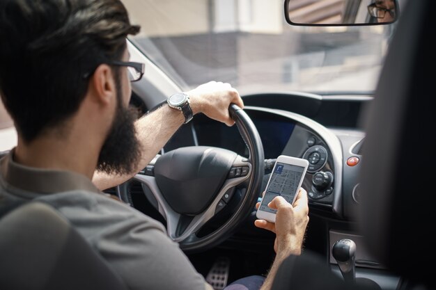 Hombre usando el teléfono móvil mientras se conduce.