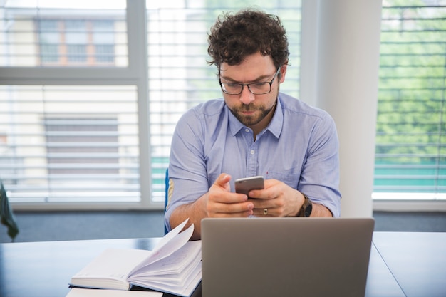 Foto gratuita hombre usando teléfono en la oficina en el escritorio