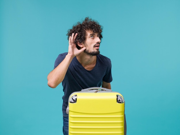 Hombre de vacaciones con maleta amarilla sobre azul