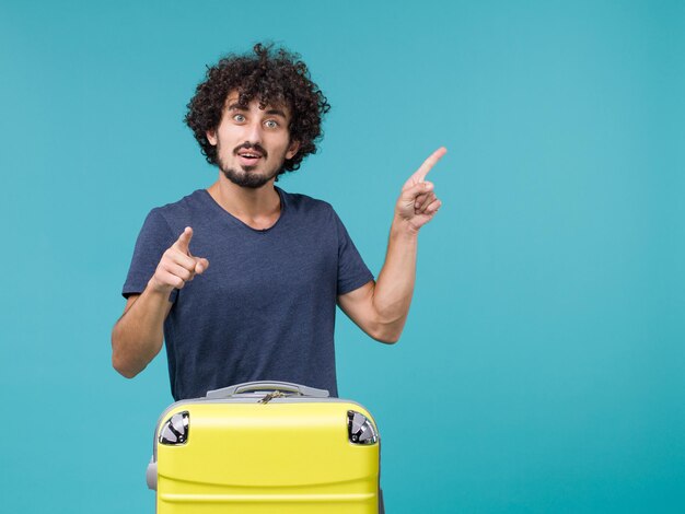 Hombre de vacaciones con maleta amarilla sobre azul