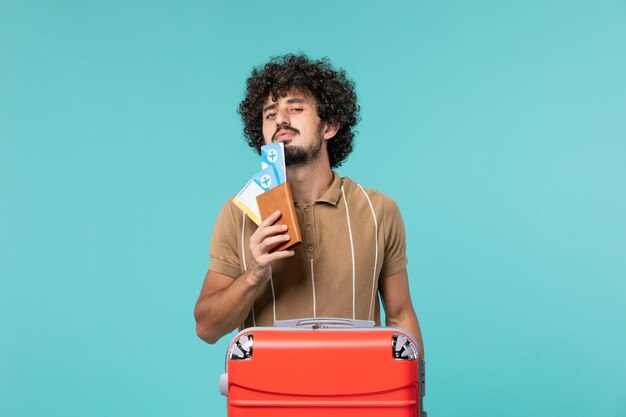 Hombre de vacaciones sosteniendo boletos en azul claro