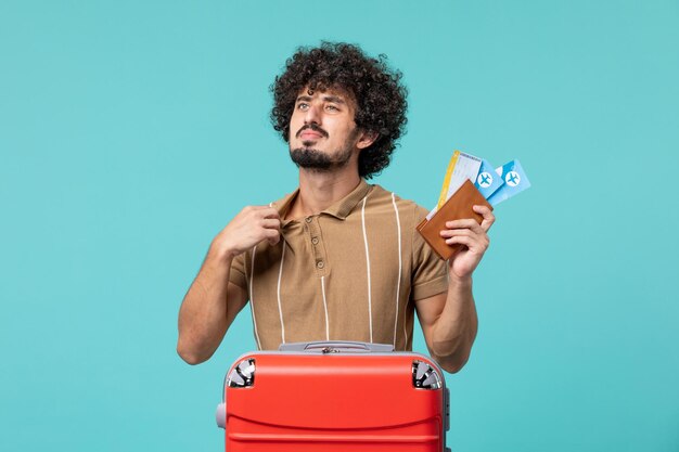 hombre de vacaciones sosteniendo boletos en azul