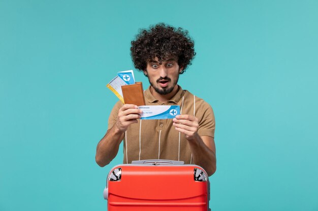 Hombre de vacaciones sosteniendo boletos y leyendo en azul