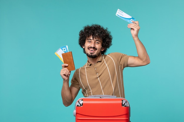 Hombre de vacaciones sosteniendo boletos sonriendo en azul