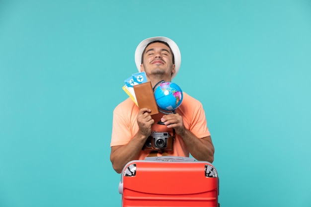 Foto gratuita hombre de vacaciones sosteniendo un globo terráqueo y entradas en azul